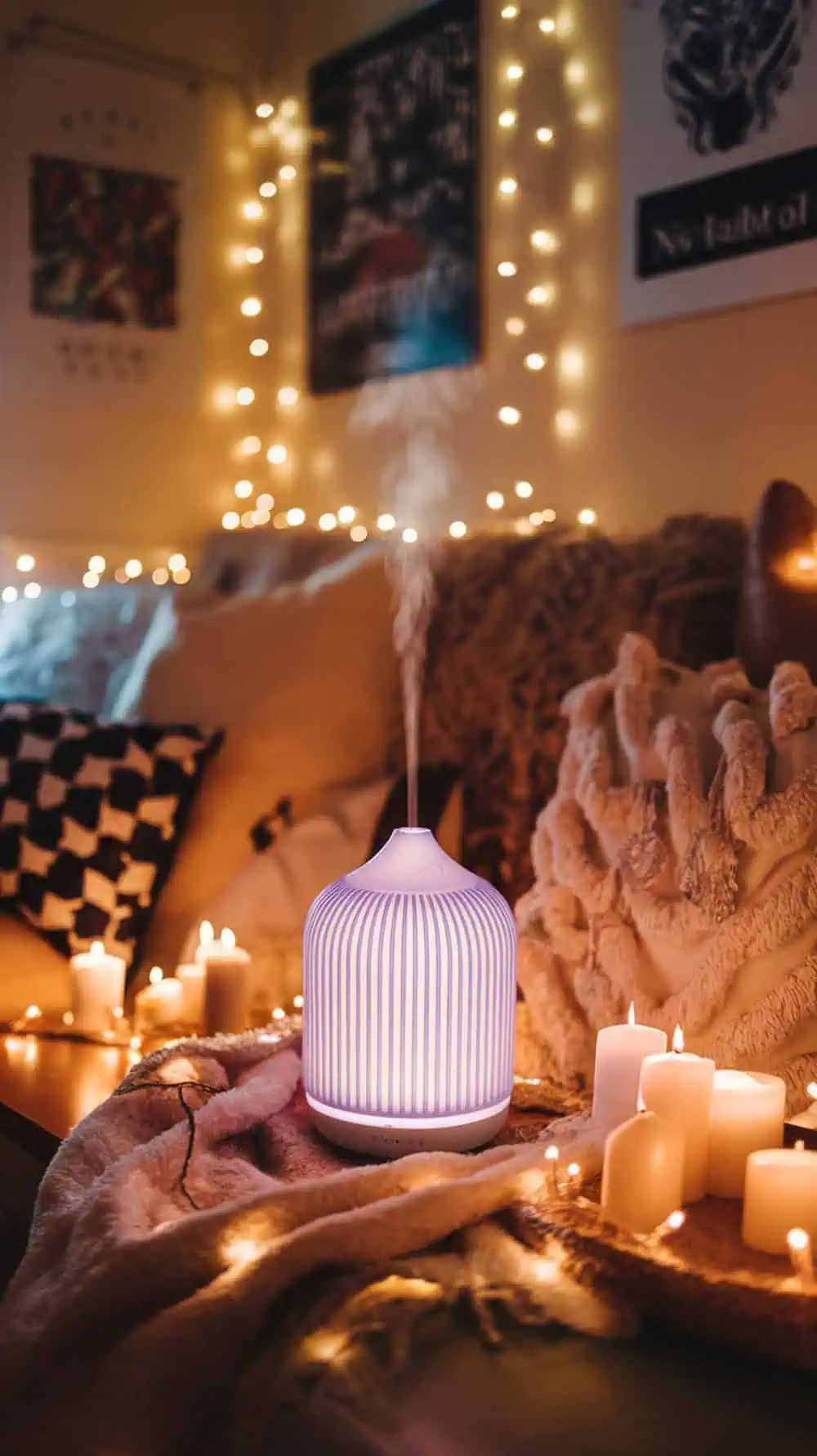 A cozy dorm room with an essential oil diffuser emitting steam, surrounded by candles and string lights.