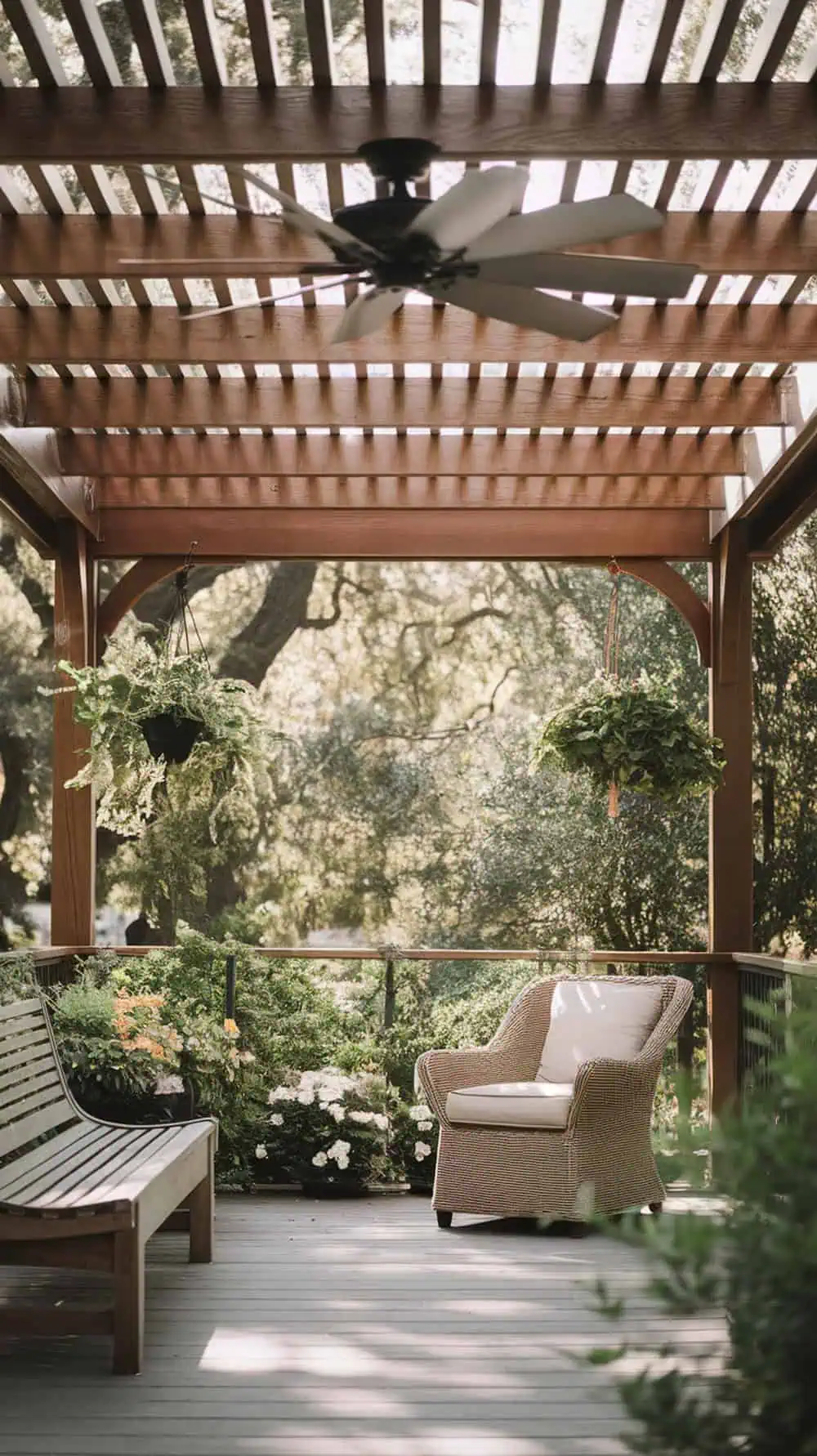 A pergola with a ceiling fan and comfortable seating surrounded by plants.
