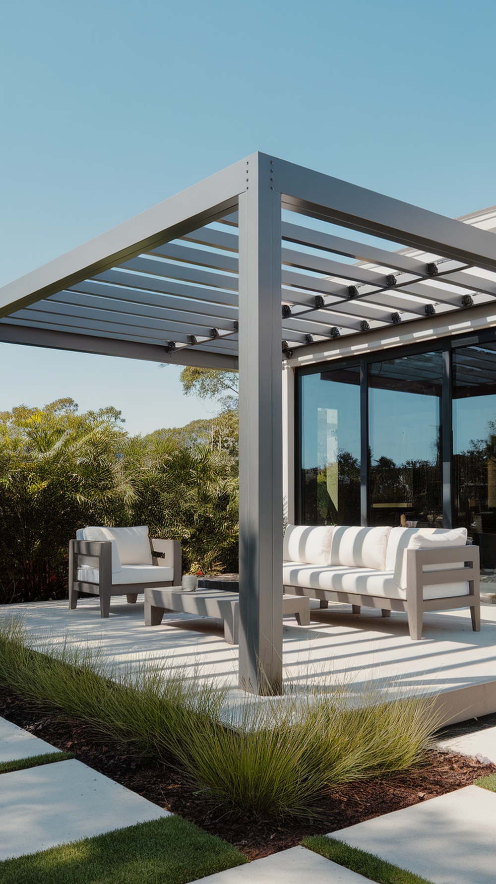 A sleek metal pergola over a modern seating area on a porch surrounded by greenery.