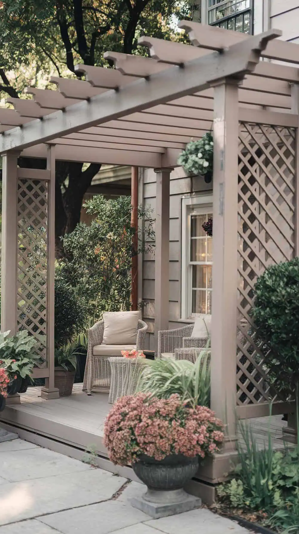 A front porch pergola with lattice panels on the sides, surrounded by plants and flowers.