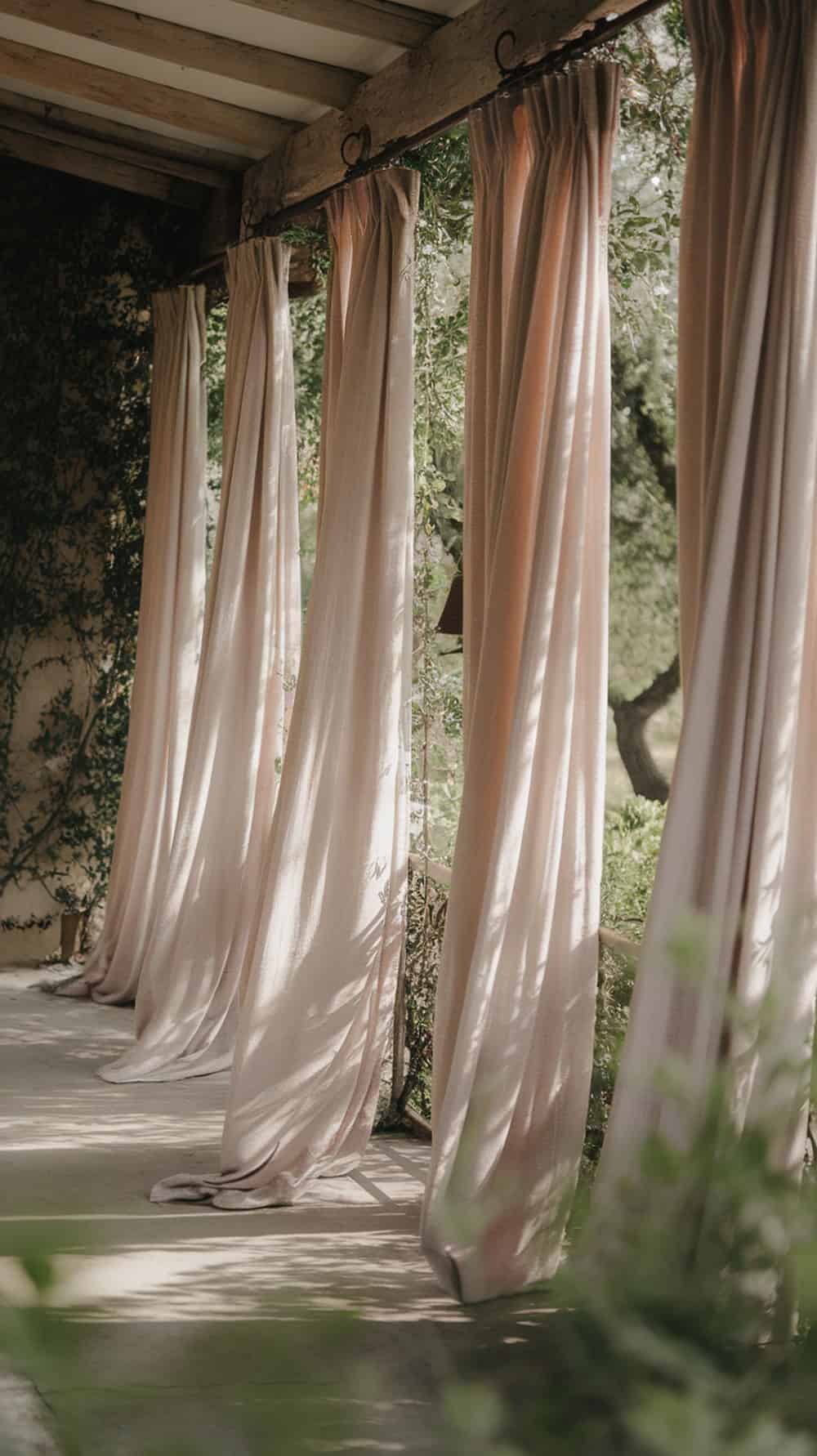 Curtain panels hung from wooden rods on a porch, creating a cozy atmosphere.