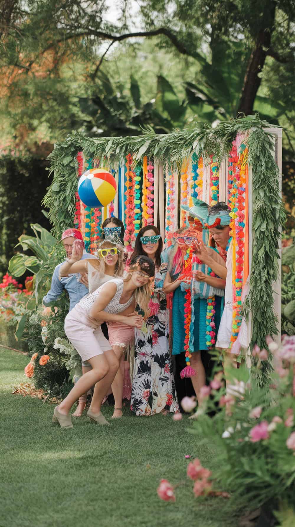 A group of friends enjoying a summer photo booth with colorful props and decorations.
