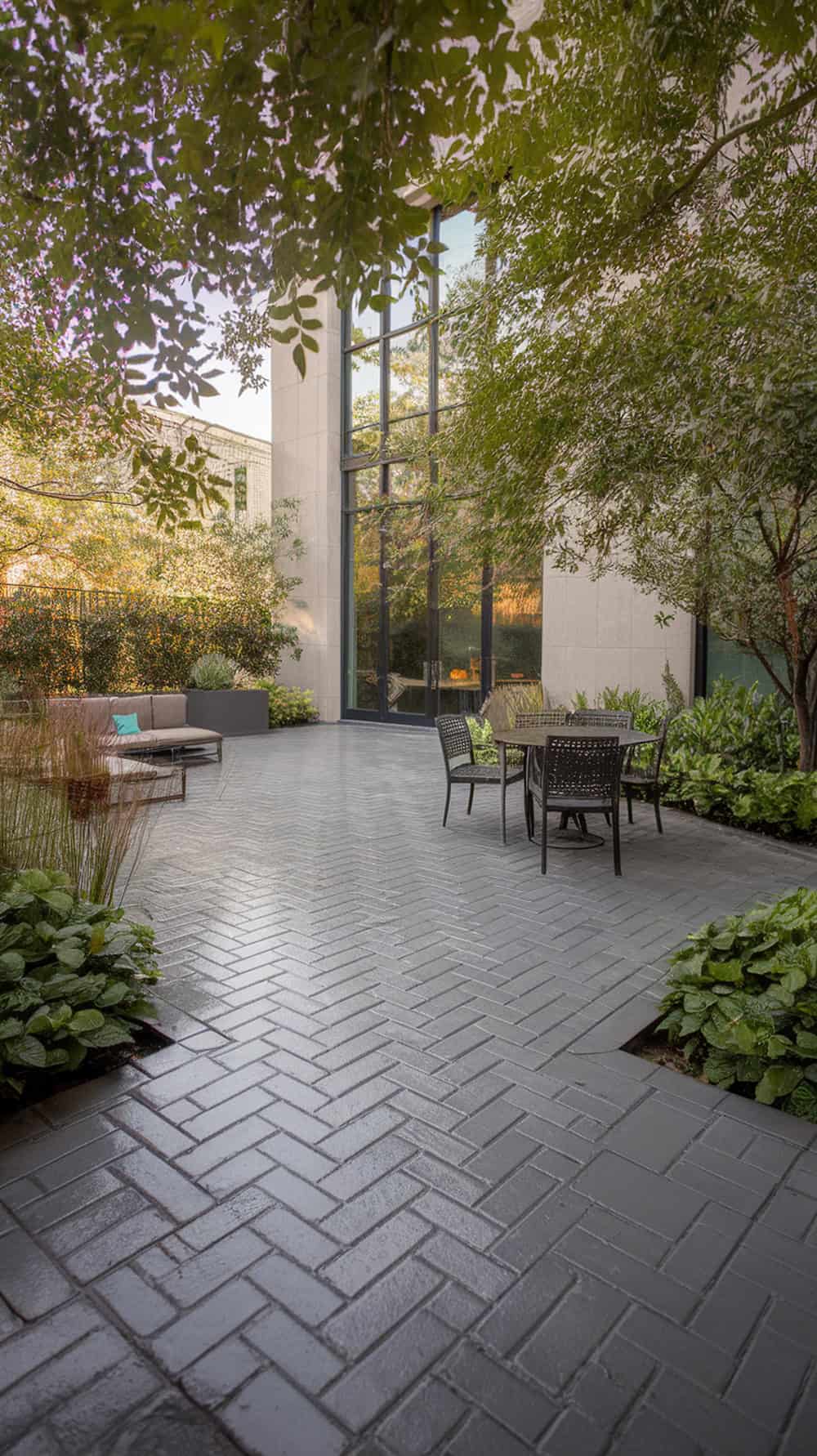 Patio with herringbone brick stamp design surrounded by greenery