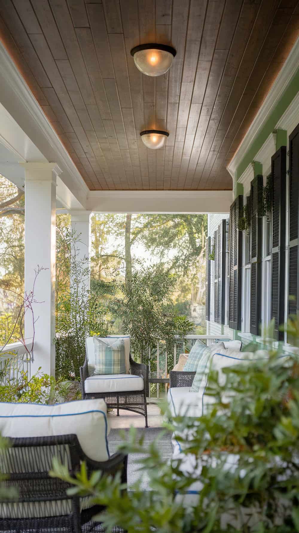 A porch with a stained tongue and groove ceiling, showcasing cozy seating and plants.