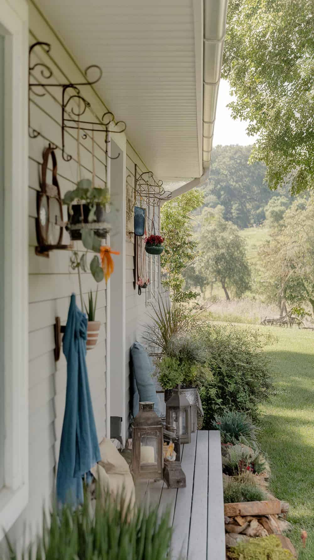 Narrow front porch with wall-mounted hooks displaying hanging plants and decor.